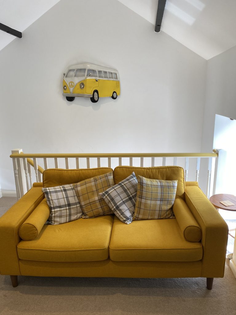 a yellow sofa in a white room with a campervan picture in the background
