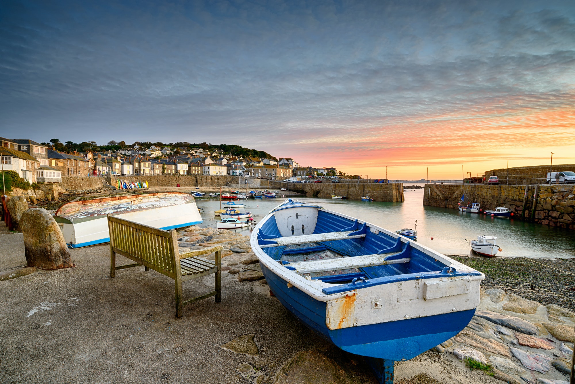 Sunrise at Mousehole harbour with a boat on the harbour wall and pink sky in the background